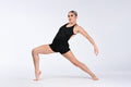 A woman in a black sleeveless leotard poses in a deep side lunge stretch against a seamless light gray studio background.