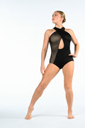 A woman modeling a black one-piece dance leotard with sheer mesh panels and a side cutout, posed against a seamless white studio background.